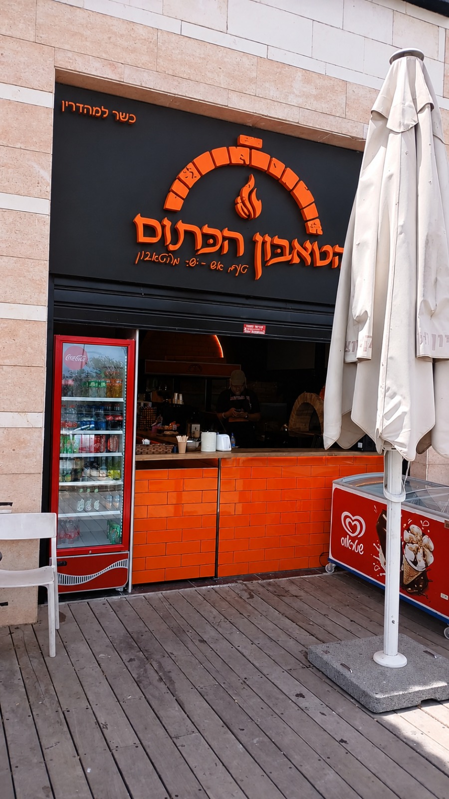 חזית הטאבון הכתום בשעת בין הערביים, מאפים חמים בחלון וטאבון בוער בצד